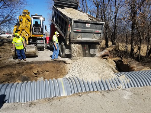 Photo of a dump truck pouring rock on to the road